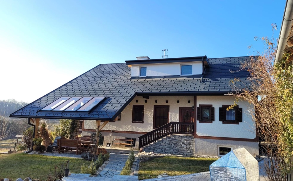 Einfamilienhaus mit großem Steildach, schwarzen Dachziegeln und integrierten Dachfenstern